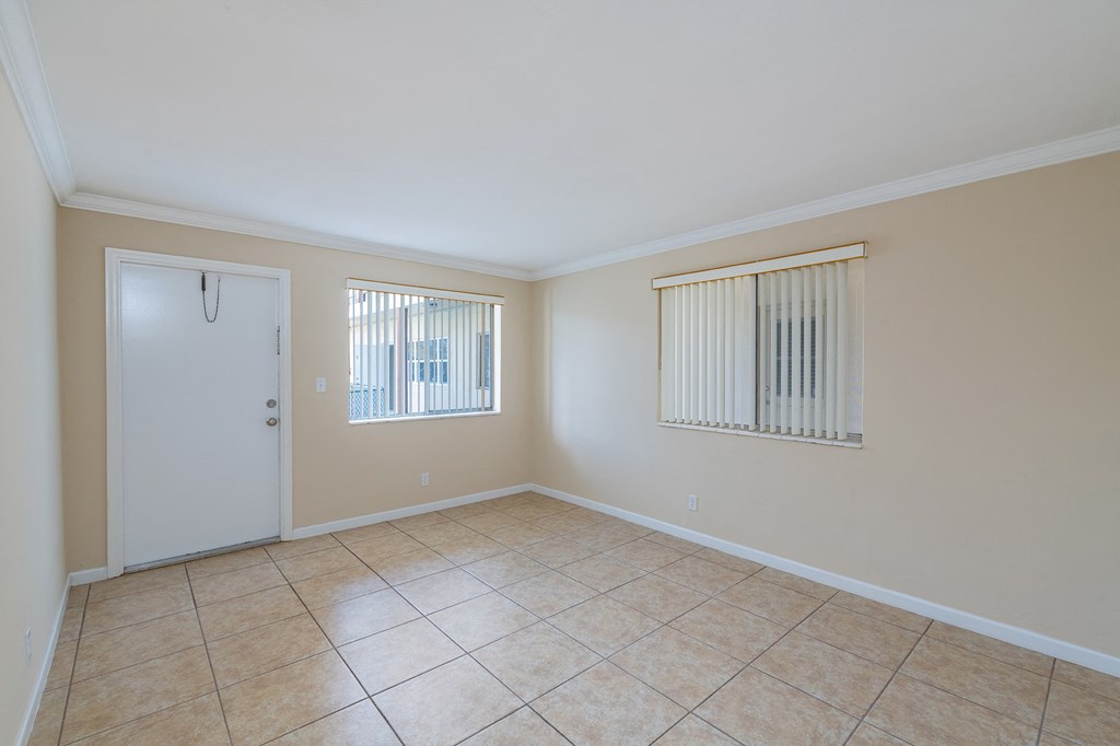 an empty living room with a door to a closet and a tiled floor