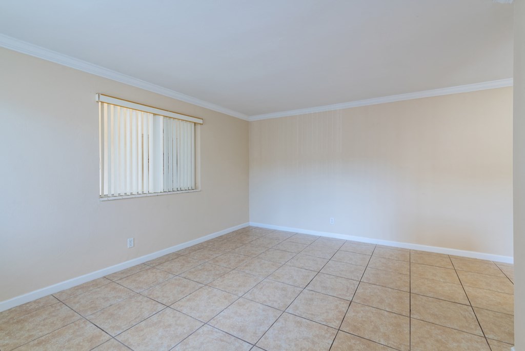 an empty living room with a window and a tiled floor