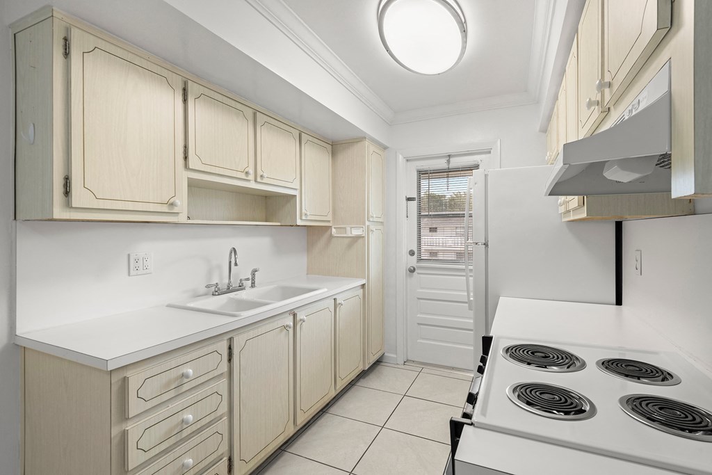 a kitchen with ivory cabinets and white counter tops and a stove and sink