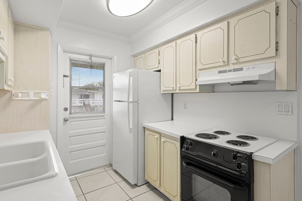 a white kitchen with a stove and a refrigerator