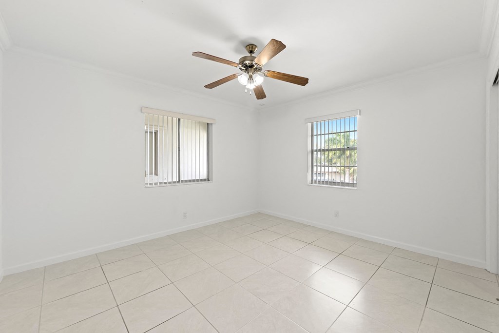 an empty living room with a ceiling fan and tiled floors