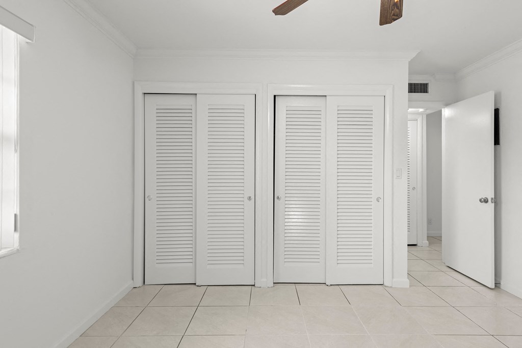 a white hallway with white shutters on the closet doors