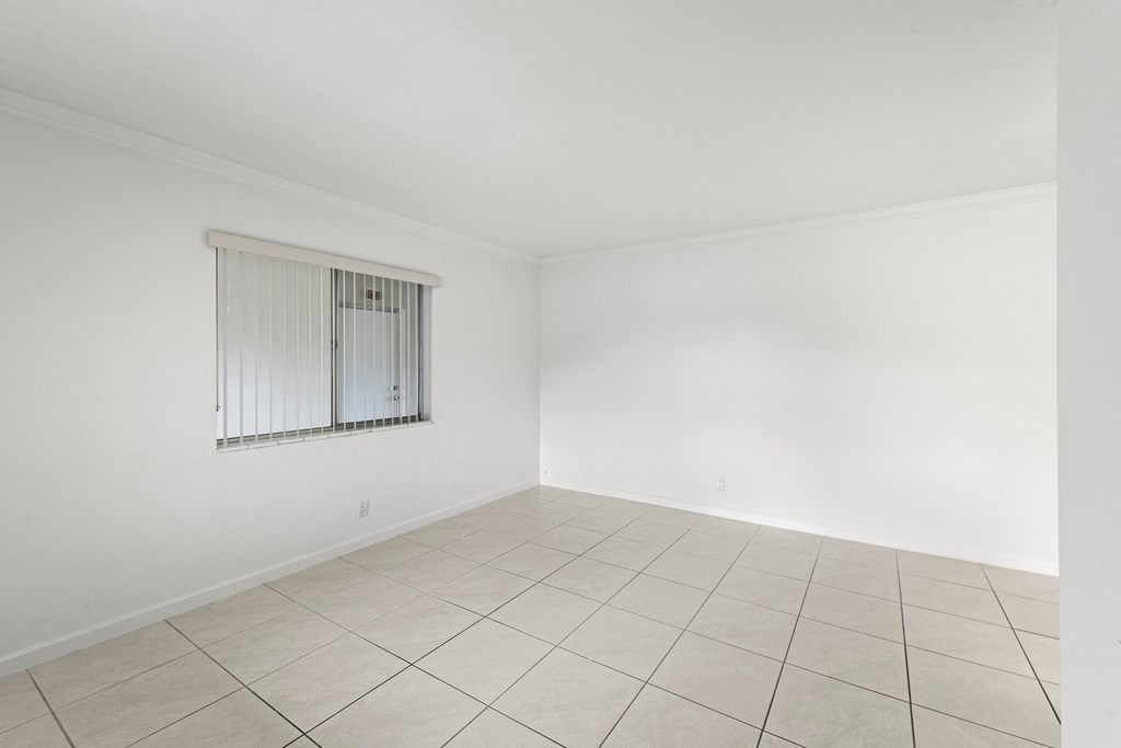 an empty living room with white walls and tiled floor and a window