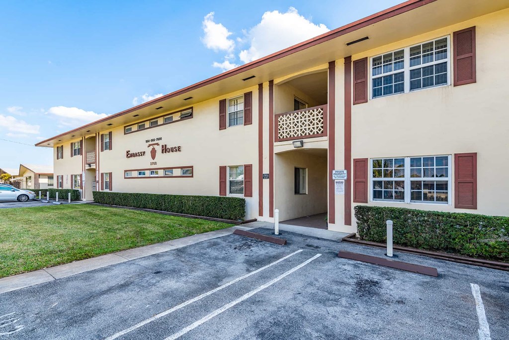 a building with a parking lot and a lawn in front of it