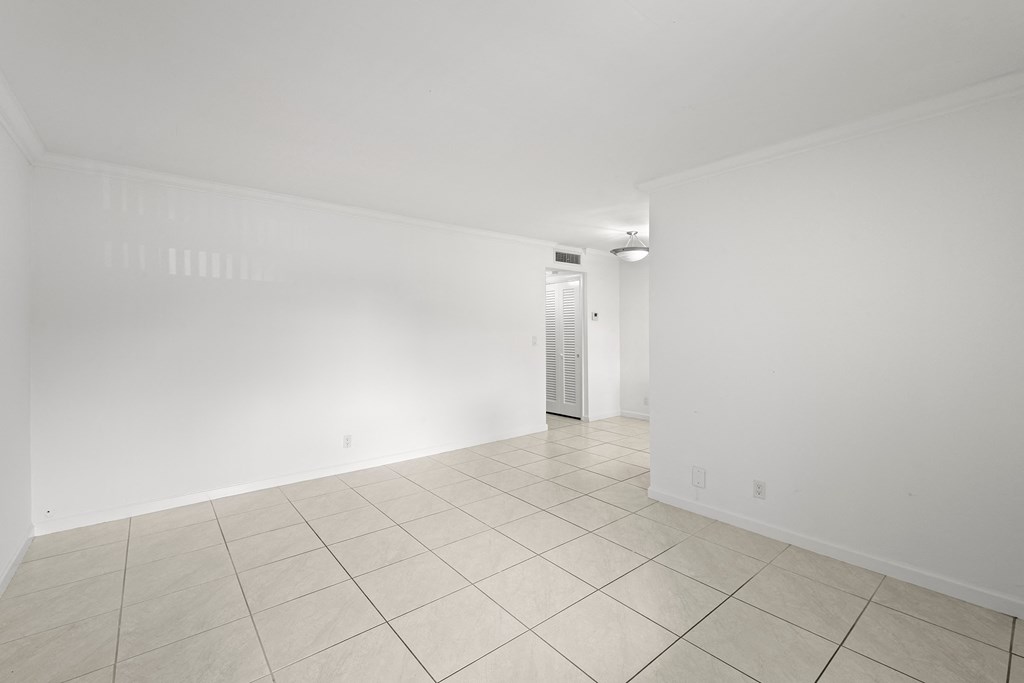 the living room and dining room of a house with white walls and tiled floors