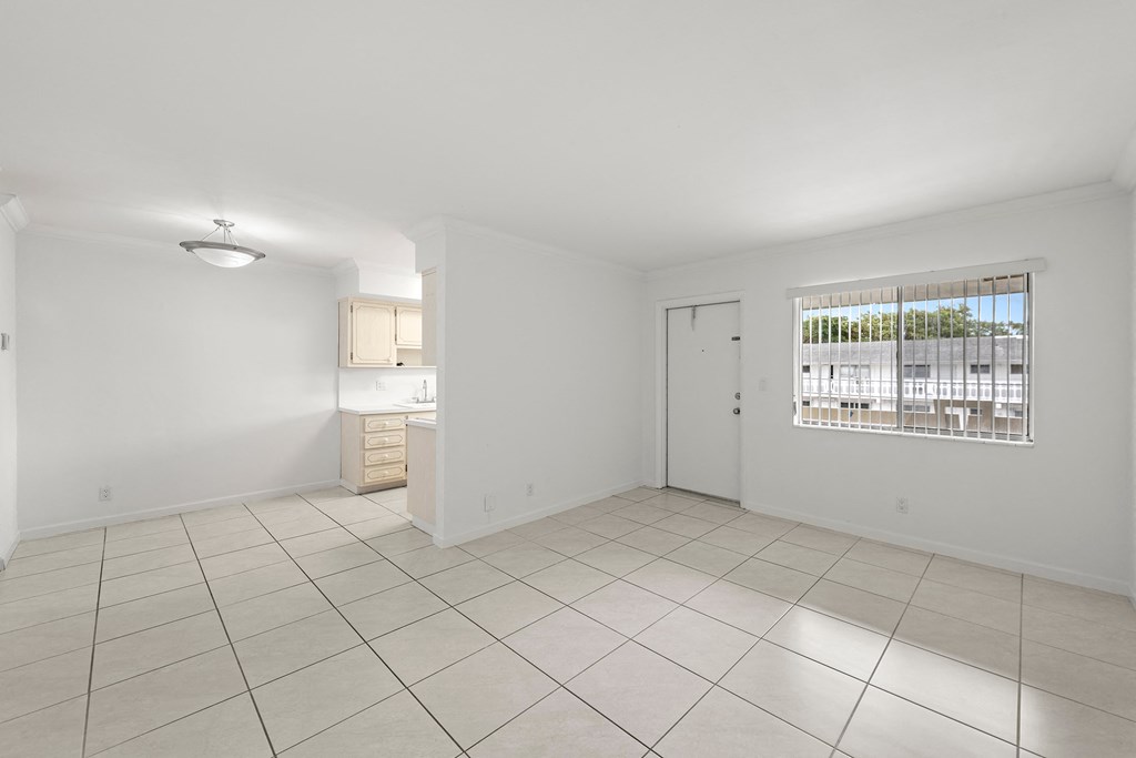 the living room and kitchen of a house with a large tiled floor