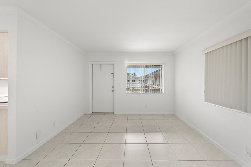 the living room and dining room of a house with white walls and tiled floors