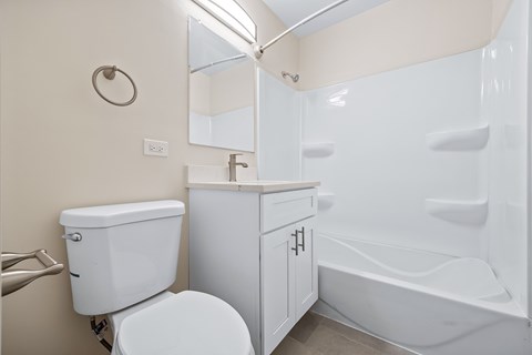 A white toilet sits next to a white sink in a small bathroom.