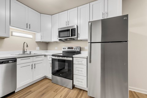 A kitchen with white cabinets and a stainless steel refrigerator.