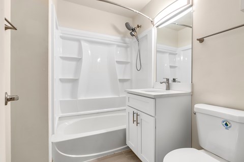A white bathroom with a tub, sink, and toilet.