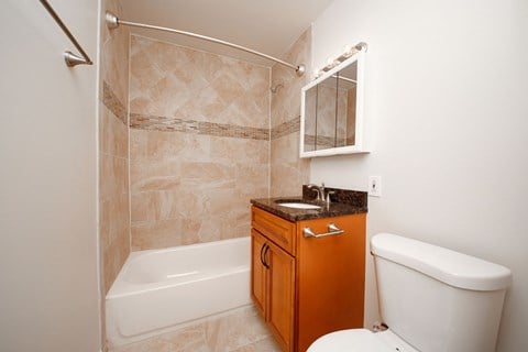 A bathroom with a white tub, a sink, and a toilet.