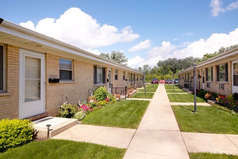 A row of houses with a sidewalk in front.