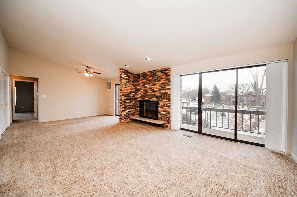 an empty living room with a fireplace and a sliding glass door