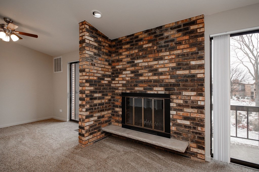 an empty living room with a brick fireplace and a window
