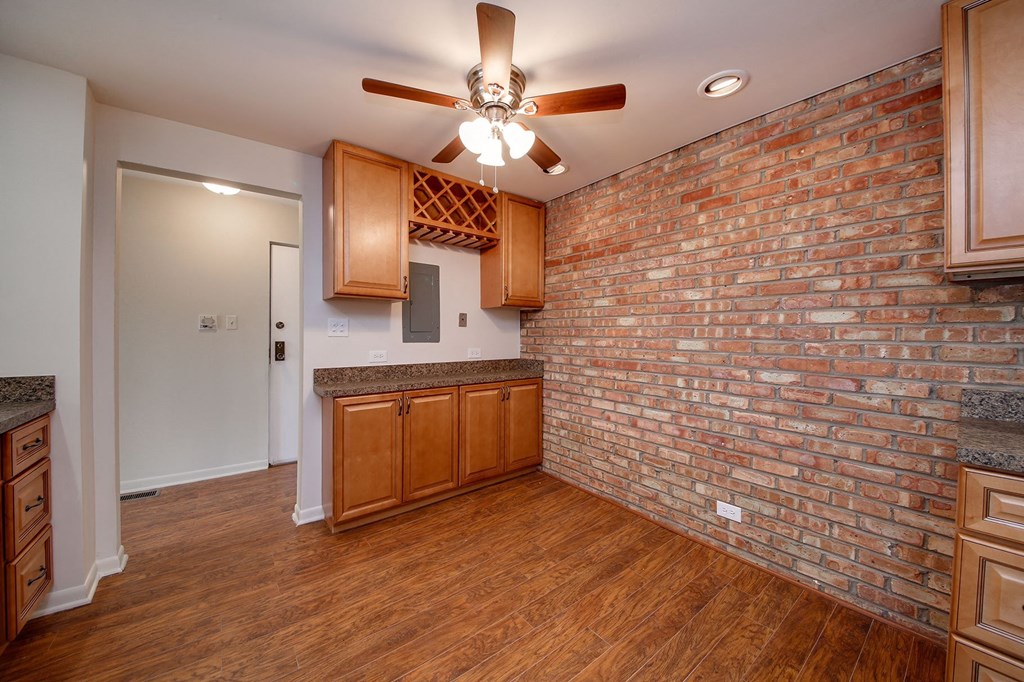 an empty living room with a brick wall and a ceiling fan