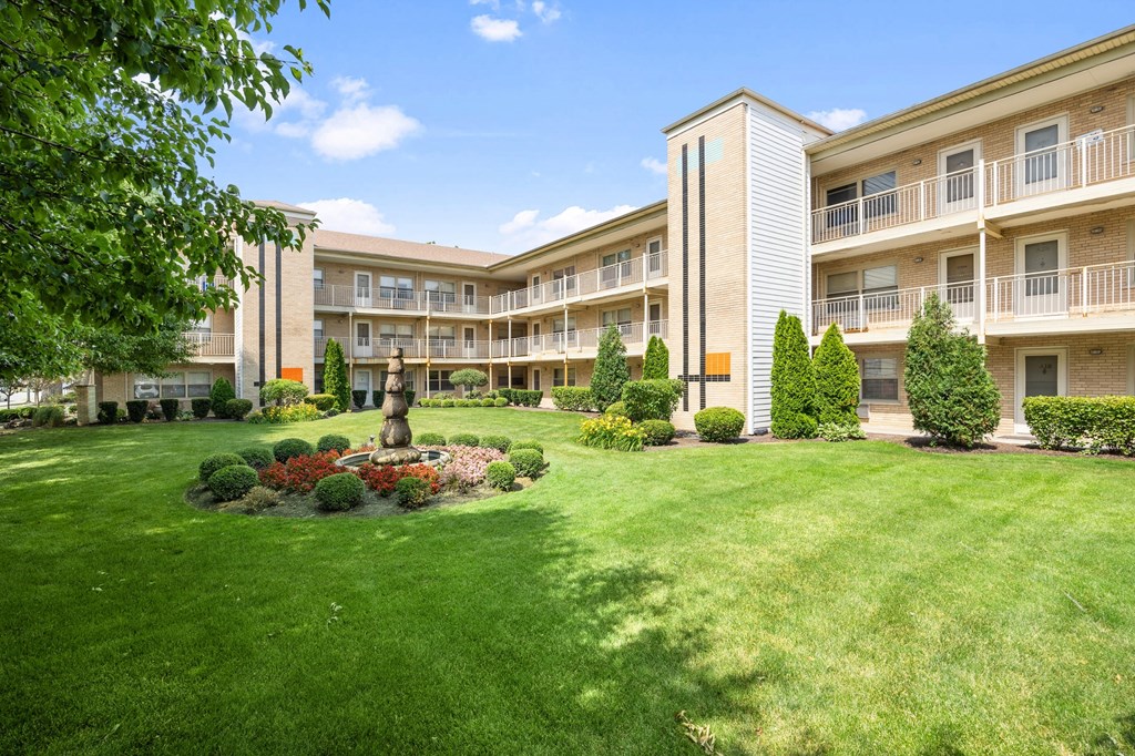 the view of an apartment building with a green lawn and a fountain