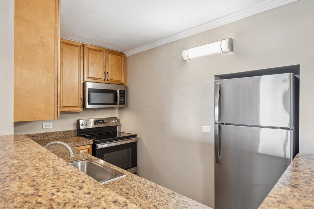 a kitchen with granite counter tops and a stainless steel refrigerator