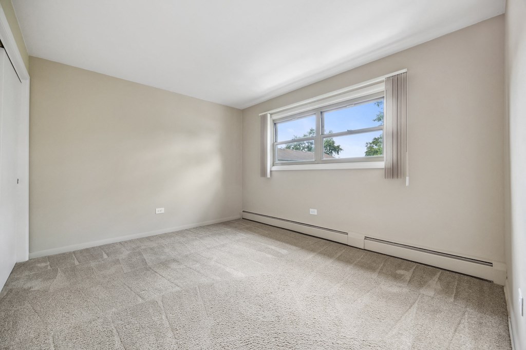 an empty living room with a window and white walls