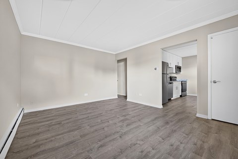 A spacious room with wooden flooring and white walls.