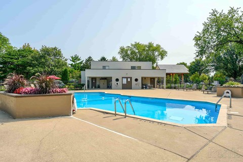 A large outdoor swimming pool with a diving board and a building in the background.