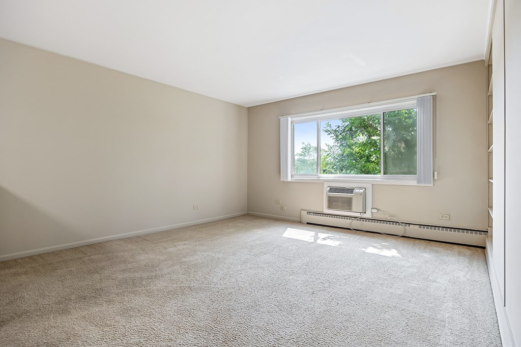 A room with a window and a wall-mounted air conditioner.
