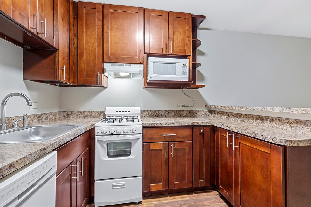 A kitchen with a white stove and a white microwave above it.