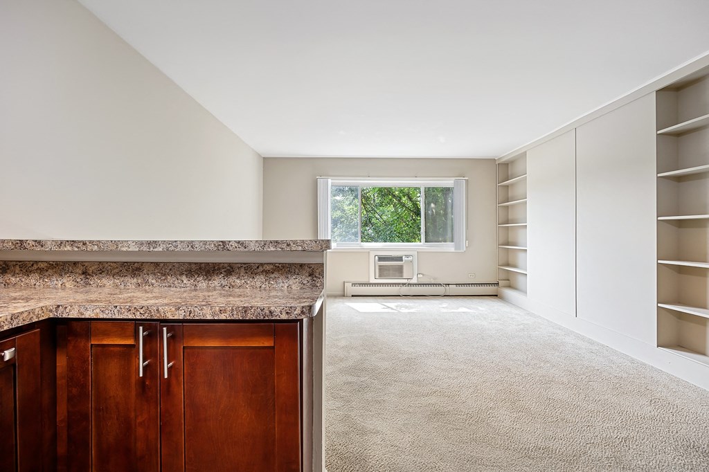 A kitchen with brown cabinets and a marble countertop.
