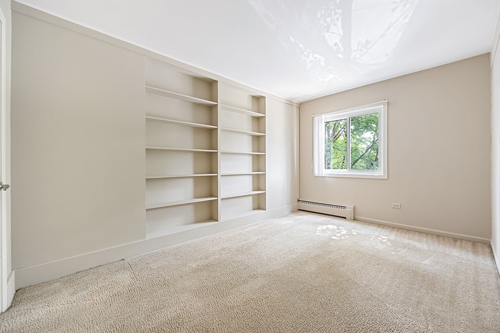 A room with a window and a carpeted floor.