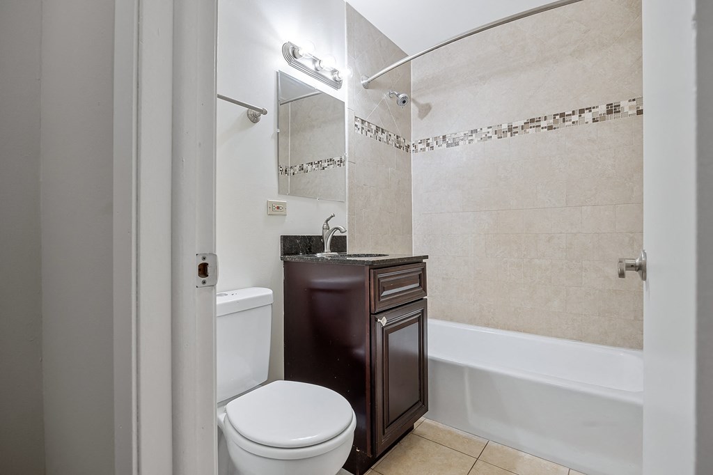A white toilet sits next to a brown cabinet in a bathroom.