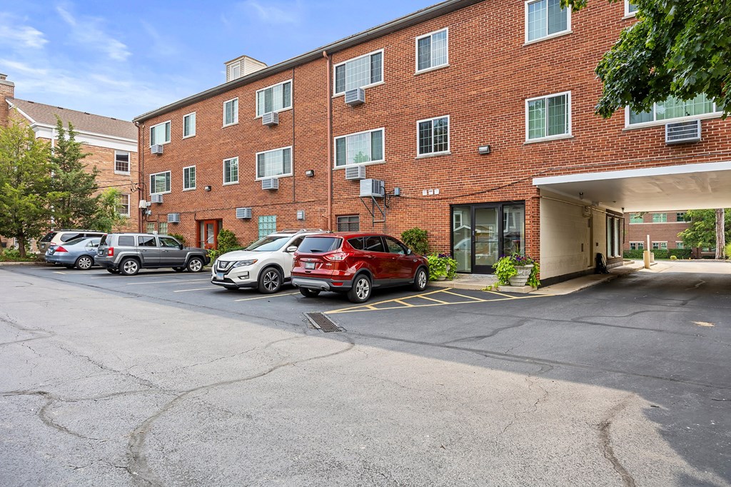 A red car is parked in front of a brick building.