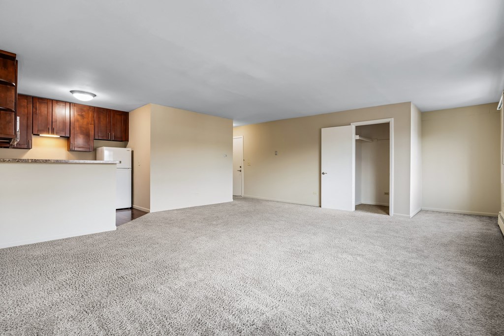 A spacious empty room with carpeted floor and white walls.