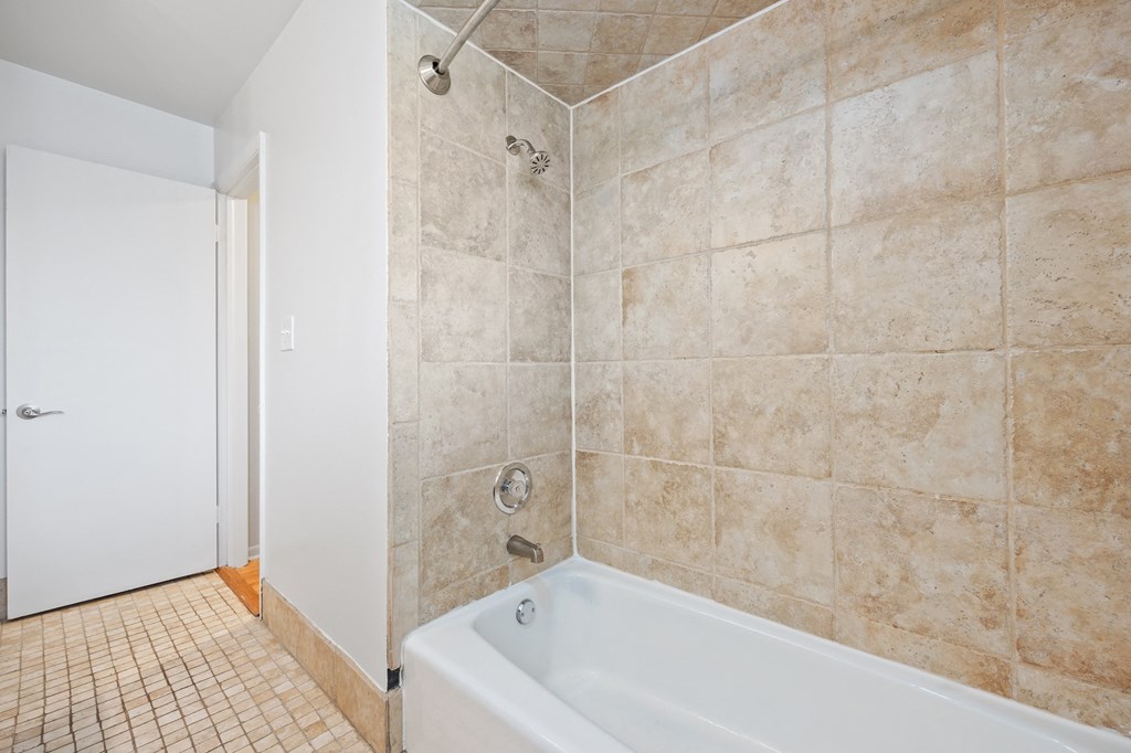 a tiled bathroom with a tub and a shower