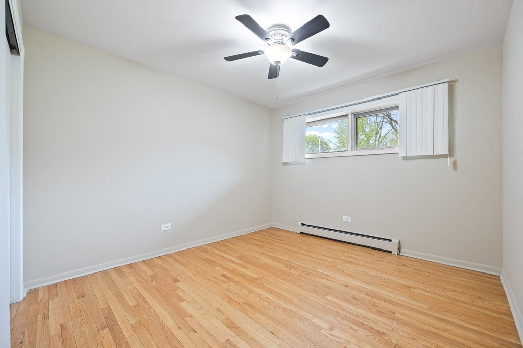 an empty living room with wood flooring and a ceiling fan