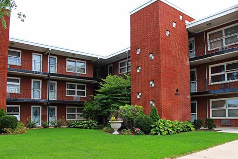 A red brick building with a green lawn in front.