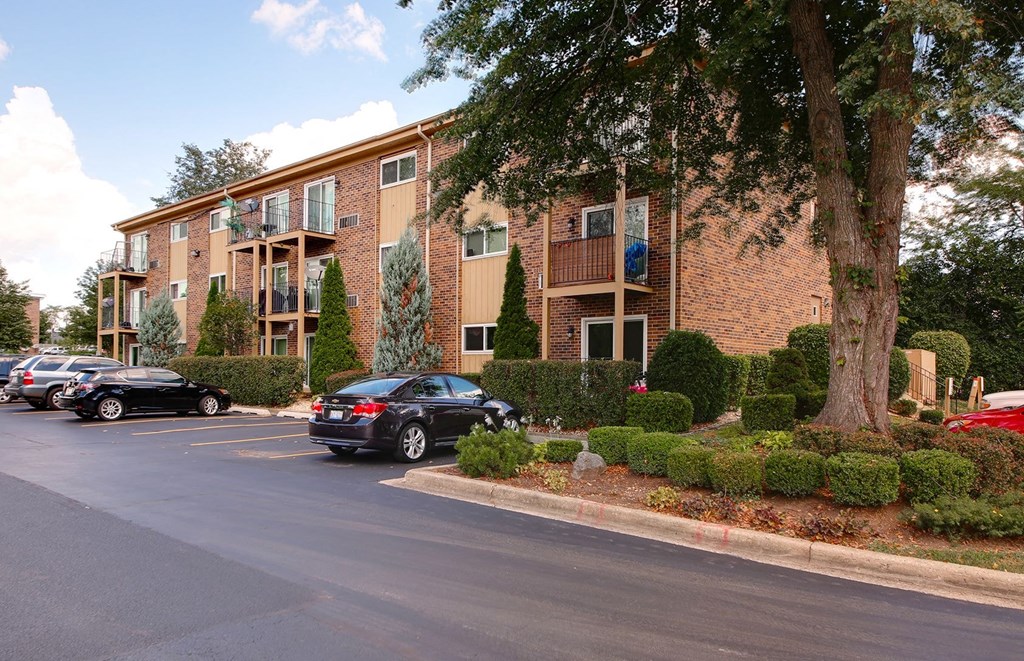 a parking lot in front of an apartment building with cars parked