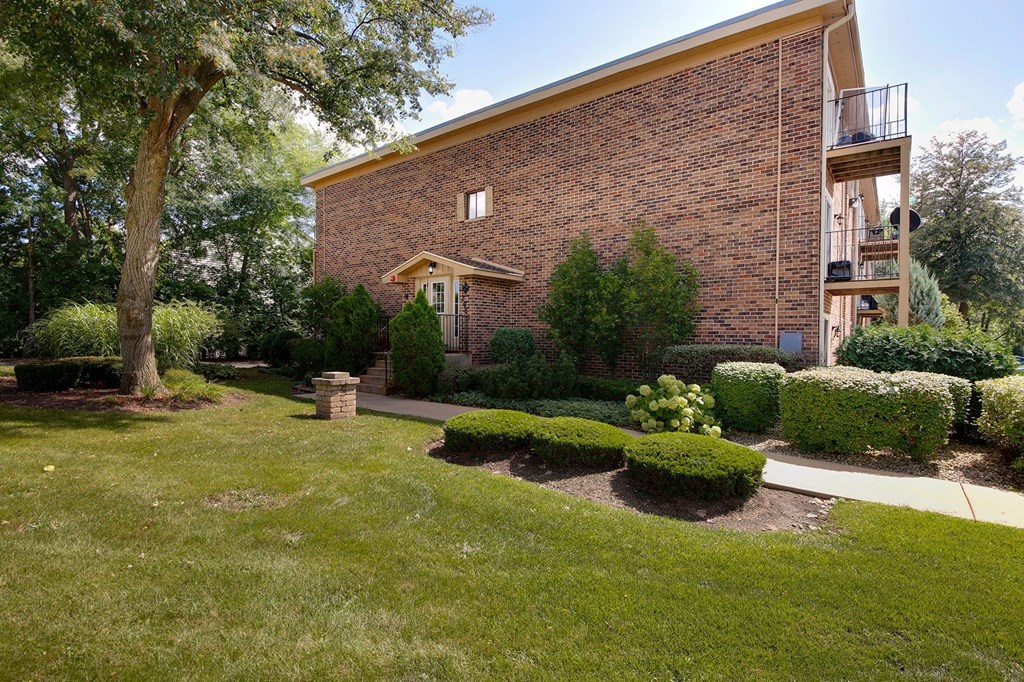 the front of a brick building with a yard and trees