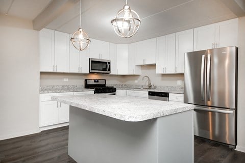 a white kitchen with stainless steel appliances and a marble counter top