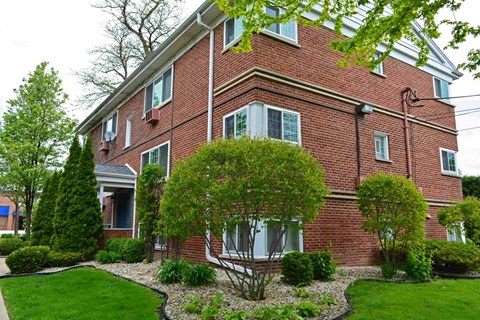 A red brick house with a green lawn in front.