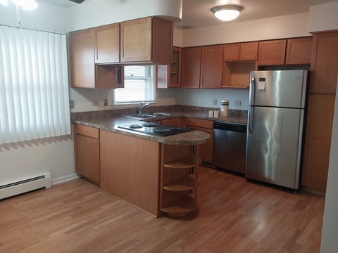 A kitchen with wooden cabinets and a stainless steel refrigerator.