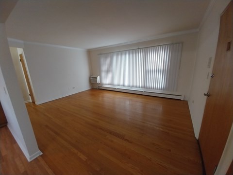 A room with wooden floors and a window with blinds.