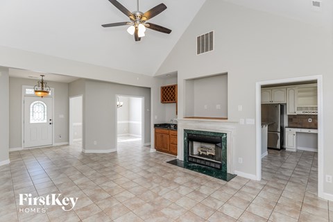 A spacious living room with a fireplace and a ceiling fan.