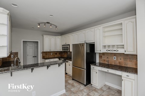 A kitchen with a stainless steel refrigerator and white cabinets.