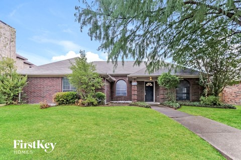 a brick house with a lawn and a sidewalk