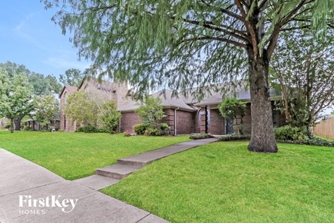 a brick house with a lawn and a tree in front of it