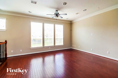 an empty living room with wood floors and a ceiling fan