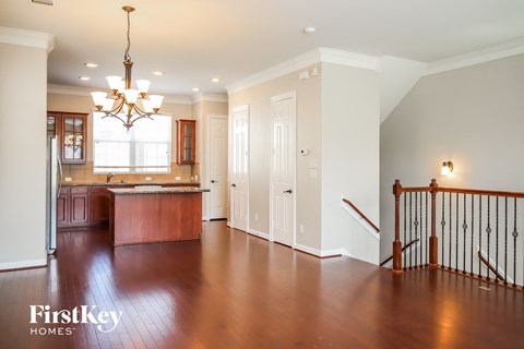 an empty living room and kitchen with a staircase and a chandelier