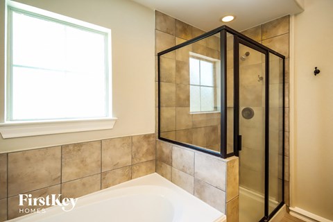 a walk in shower and a tub in a tiled bathroom