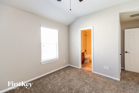 a bedroom with a carpeted floor and a door to a bathroom