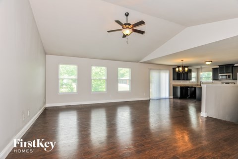 A spacious room with a ceiling fan and wooden flooring.