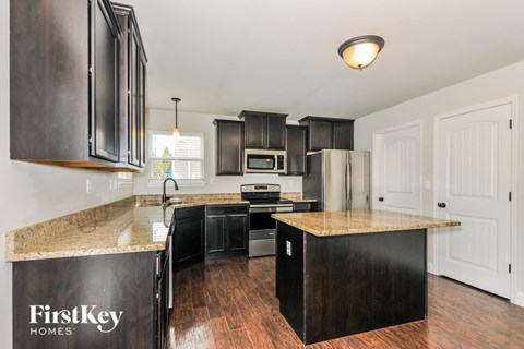 A kitchen with dark wood cabinets and a granite countertop.